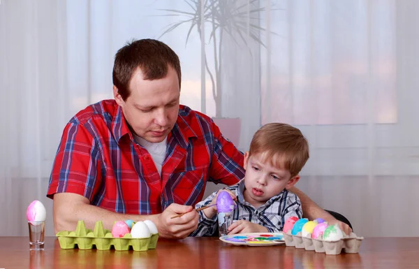Father and son get ready for Easter and paint chicken eggs