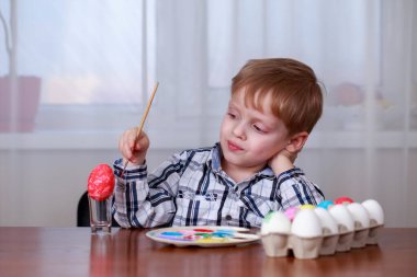 Küçük çocuk yumurta renkli boyalar ile boyar.