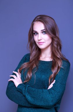 Gri arka planda yeşil kazaklı güzel bir kız.