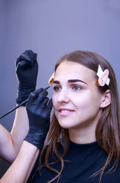 Beautician performs eyebrow dyeing procedure in the salon