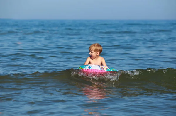 Little boy floats on an inflatable boat at sea