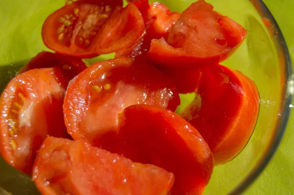 Fatias de tomate em uma tigela de vidro no fundo verde close-up — Fotografia de Stock