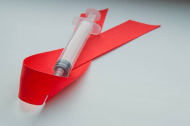 Farkındalık kırmızı kurdele ve şırınga beyaz zemin üzerine: Dünya günü karşı AIDS, HIV ile yaşayan Aralık ayında sağlık insanlar için genel destek teşviki