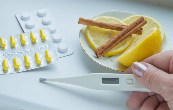 Das Thermometer in den Händen, Tabletten, Zitrone mit Zimtbehandlung — Stockfoto
