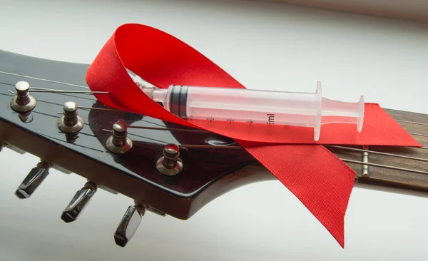 Guitar, rock music, a syringe and red ribbon - symbol of fight against AIDS — Stock Photo, Image