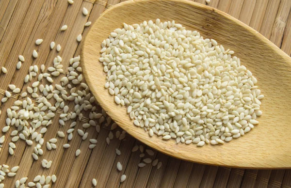 Organic natural sesame seeds on wooden spoon and a bamboo napkin — Stock Photo, Image