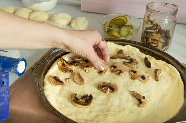 Las manos femeninas extendieron los hongos sobre la pizza, comida casera —  Fotos de Stock