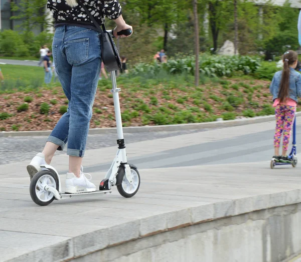 Vrouw en haar dochter rit samen buiten in het Park op de scooter — Stockfoto