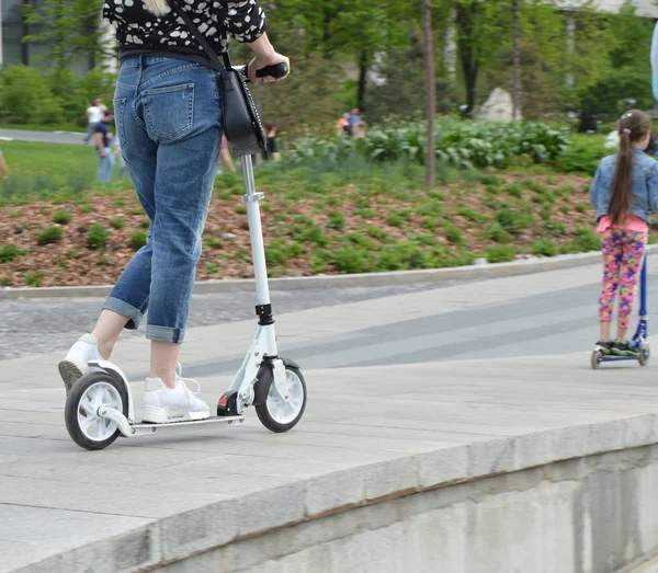 Kvinna och hennes dotter rida tillsammans utomhus i parken på skoter — Stockfoto