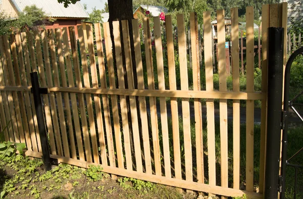 New picket fence and black metal poles, built in the garden — Stock Photo, Image