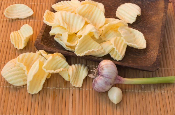 Patatine croccanti in una ciotola di legno accanto al bulbo d'aglio — Foto Stock