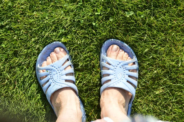Female feet in blue flip-flops on green grass, dirty after working in the garden — Stock Photo, Image