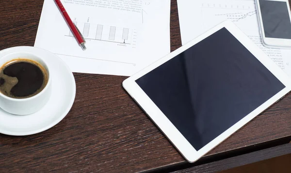 İşadamı dijital tablet, smartphone, fincan kahve ve grafikler ile çalışma alanı. Bir başlangıç iş kavramı