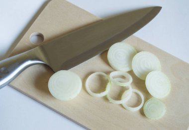 Bir mutfak bıçağı ile bir kesme tahtası üzerinde taze soğan dilimlenmiş