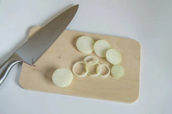 Свежий лук, нарезанный на разделочной доске кухонным ножом — стоковое фото