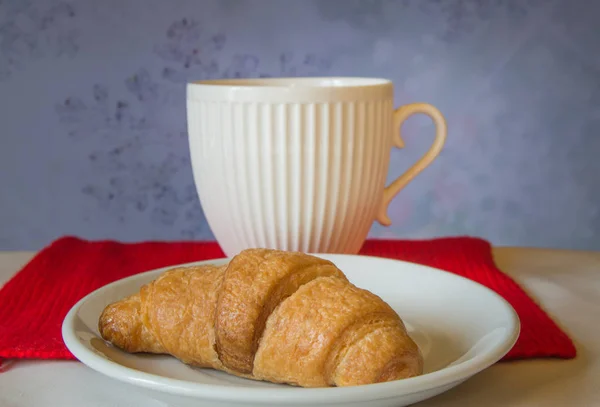 Świąteczne śniadanie - White Cup i rogalika na tle czerwonym szalikiem z dzianiny — Zdjęcie stockowe