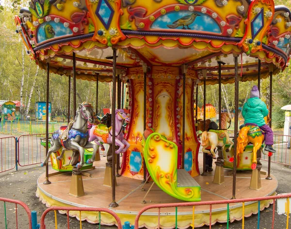 Children ride on the horses on the colorful carousel in the Park — ストック写真