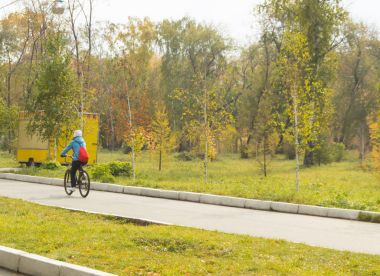 Bir kız bir bisiklet bir şehirde Park ile sonbaharda gidiyor