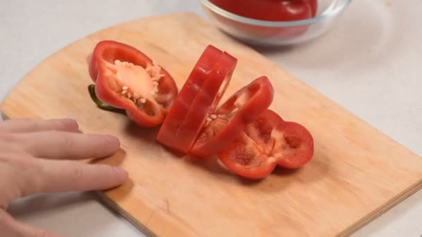 Fechar-se de homens mão cortar pimenta vermelha em uma tábua de corte e colocá-lo em uma tigela de vidro — Vídeo de Stock