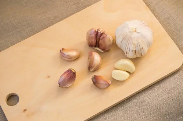 Cloves and clove of garlic on wooden cutting Board — Stock Photo, Image