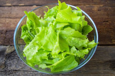 Koyu ahşap arka plan üzerinde cam kapta sağlıklı taze salata