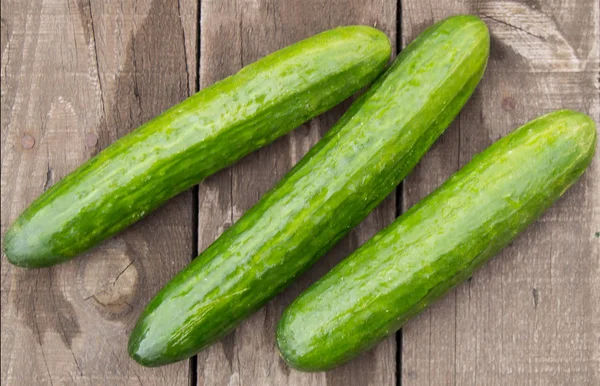 Fresh cucumbers on old wooden background, top view — Stock Photo, Image