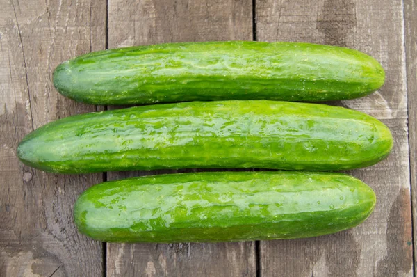 Verse komkommers op oude houten achtergrond, bovenaanzicht — Stockfoto