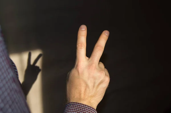 Чоловік піднімає два пальці вгору, показуючи знак перемоги, вид ззаду — стокове фото
