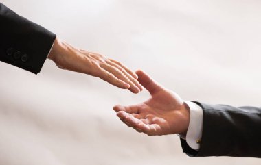İş takım elbiseli adamları birbirlerine ulaşmak için el sıkışma, yardım, anlaşma, finans