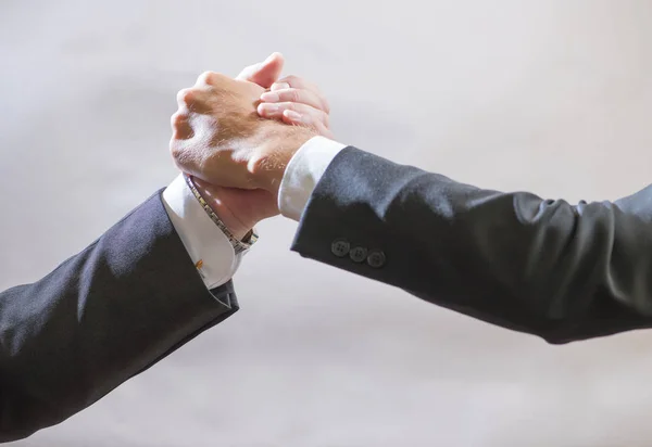 Two business partner to greet each other, branded handshake on gray background — Stock Photo, Image