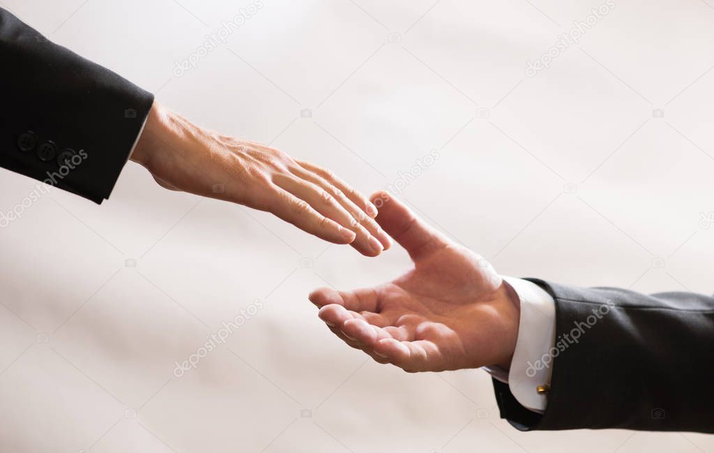 Businessmen in suits reach out to each other for handshake, help, deal, Finance