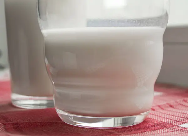 Dois copos de leite em um pano vermelho xadrez, conceito de comida saudável — Fotografia de Stock