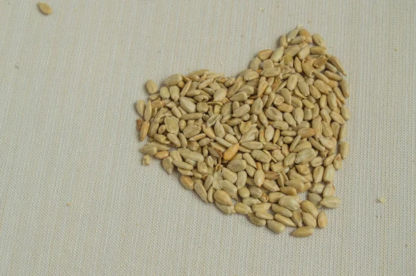Slunečnicová semena, roztroušených na stůl ve tvaru srdce, koncept zdravé stravy — Stock fotografie