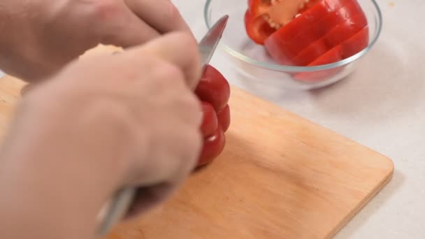 Männerhand vorsichtig und langsam mit einem Messer rote Paprika in Scheiben schneiden — Stockvideo