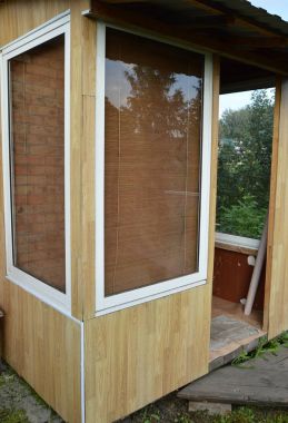 Cam kapı ve pencerelerde ahşap bir veranda. Kır evi girişi