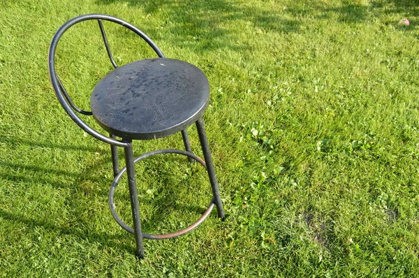 Černá kovová Barová stolička stojí na zelené trávě venku — Stock fotografie