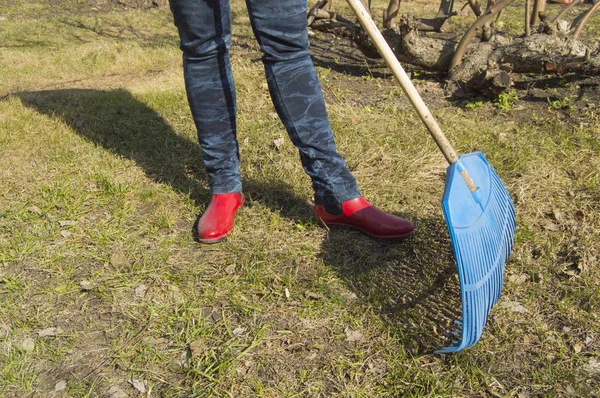 Mavi jeans ve kırmızı lastik çizme Tırmıklar, Bahçe iş ile kadın ayaklarda Close-Up