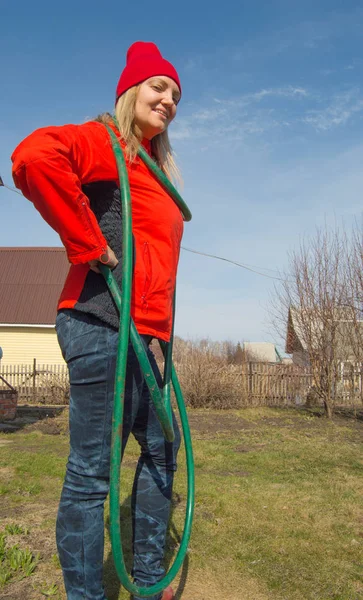 Красива усміхнена фермерка позує у своєму саду, тримаючи водопровідний шланг, сільське господарство та підприємництво — стокове фото