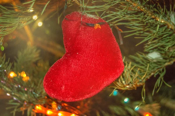 Rotes Leinen handgemachte Herzdekoration am Weihnachtsbaum auf dem Hintergrund von leuchtenden Lichtern Weihnachtsgirlanden — Stockfoto