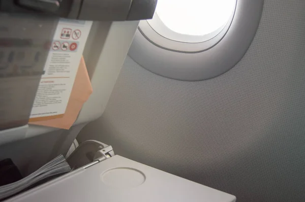 Mesa plegable, instrucciones de vuelo, cargador en el asiento delantero, ojo de buey, concepto de vuelos y viajes — Foto de Stock