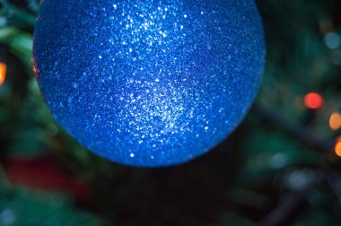 Parlak bir Noel balosu, yeşil bir Noel ağacının bulanık arka planında, çerçevedeki topun bir parçası, açık çerçeve, yakın çekim