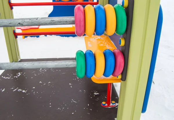 大きな色の子供のそろばん、金属フレーム上のプラスチックリング、冬雪で覆われた遊び場 — ストック写真