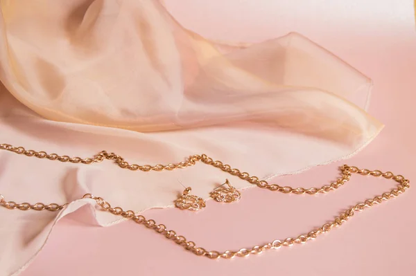 ダイヤモンド、クローズアップと美しい貴重な女性の宝石類。コピースペースとピンクシルクの背景にゴールドチェーンとイヤリング — ストック写真