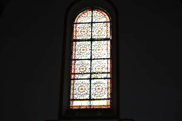 Sonnenlicht strömt durch die bunten Glasfenster in der Kirche gegen eine dunkle Wand, das Innere der katholischen Kathedrale — Stockfoto