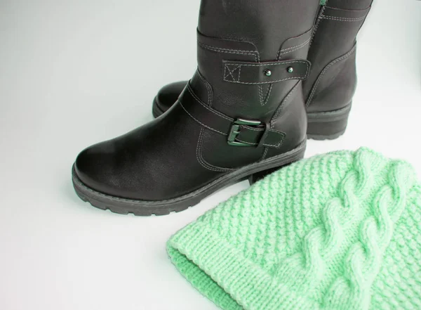 Moda invierno zapatos de mujer botas de cuero negro y sombrero de lana de punto sobre un fondo blanco, el concepto de comprar ropa de abrigo y zapatos para el invierno — Foto de Stock