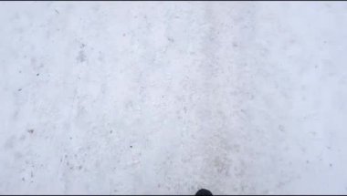 Üst manzara, kaygan bir yolda karda dikkatlice yürüyen bir adamın selfie 'si. Kışın buzda sürerken dikkatli ol. İlk kişi görünümü 4k video