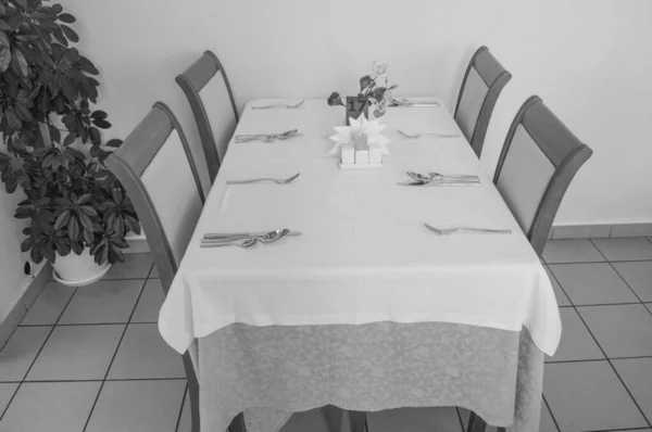 Праздничный стол со скатертью и столовыми приборами в ресторане отеля ждет гостей, вид сбоку, черно-белая рамка — стоковое фото