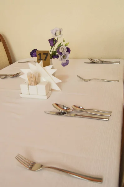 Närbild av elegant silver Bestick på ett tomt, vitt dukat bord, vertikal ram, som serverar väntar på gästerna — Stockfoto