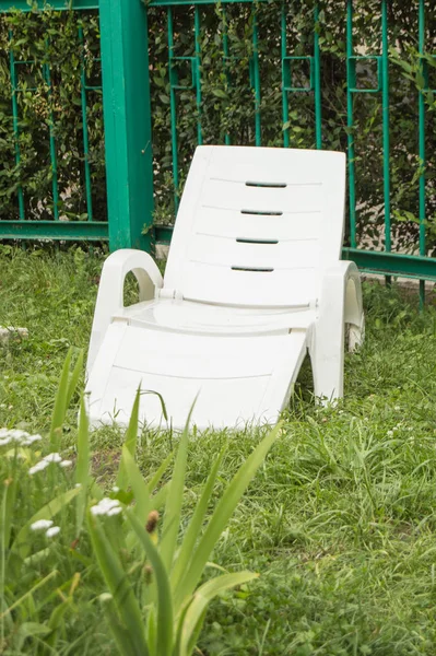 Leere weiße Plastik-Chaiselongue steht auf dem grünen Gras, in einem privaten Bereich, umzäunt von einer Hecke, Rest in einem Hotel im Resort — Stockfoto