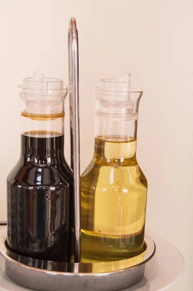Zestaw octu balsamicznego lub sosu sojowego i oliwy z oliwek w szklanych butelkach na stole w kawiarni lub restauracji, ujęcie pionowe — Zdjęcie stockowe